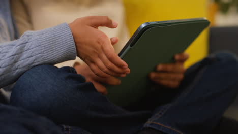 Two-Young-Boys-Sitting-On-Sofa-At-Home-Playing-Games-Or-Streaming-Onto-Digital-Tablet-4